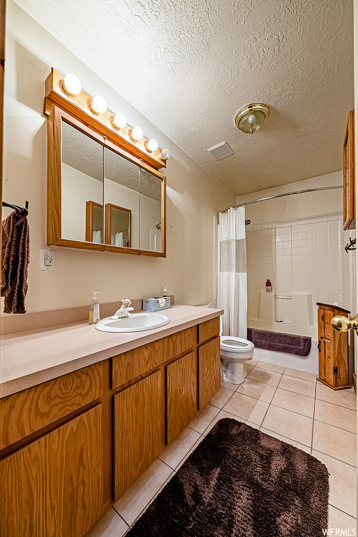 Full bathroom featuring oversized vanity, a textured ceiling, tile flooring, and toilet