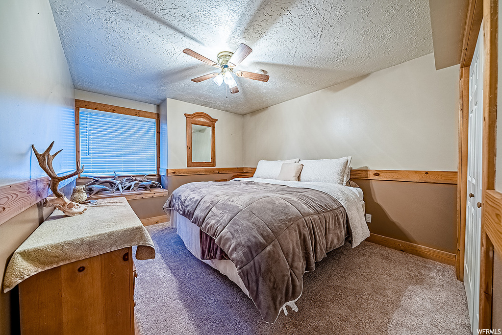 Carpeted bedroom featuring ceiling fan, a closet, and a textured ceiling