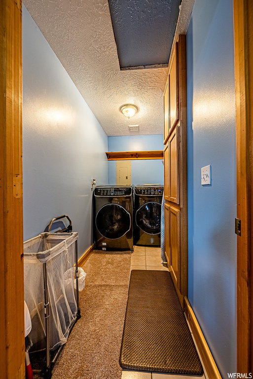Laundry room featuring light carpet, washing machine and dryer, and a textured ceiling