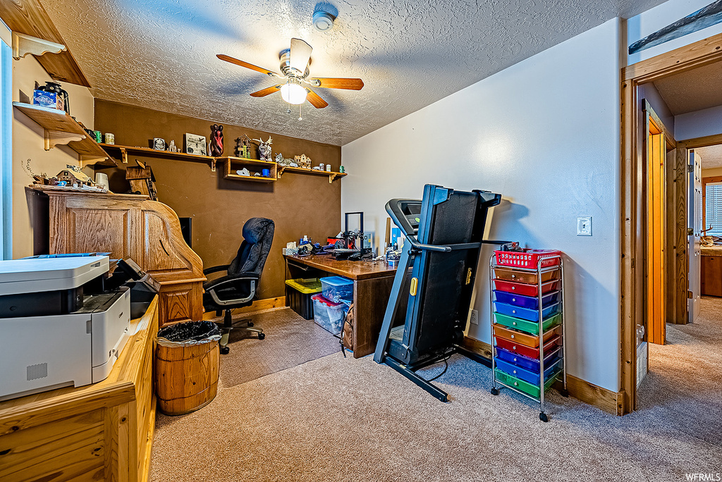 Office space featuring ceiling fan, light carpet, and a textured ceiling