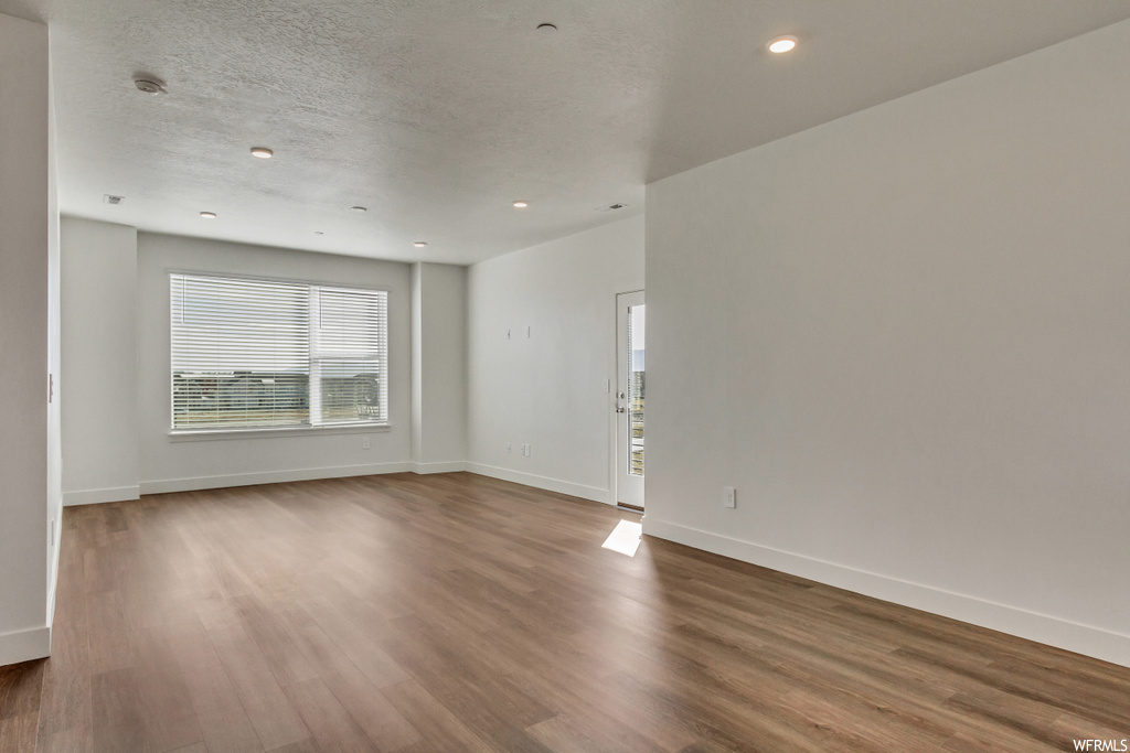 Empty room featuring a textured ceiling and dark hardwood / wood-style flooring