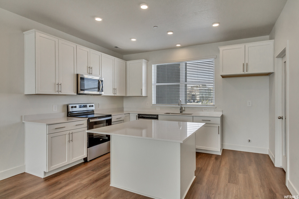 Kitchen with a center island, sink, stainless steel appliances, and white cabinetry