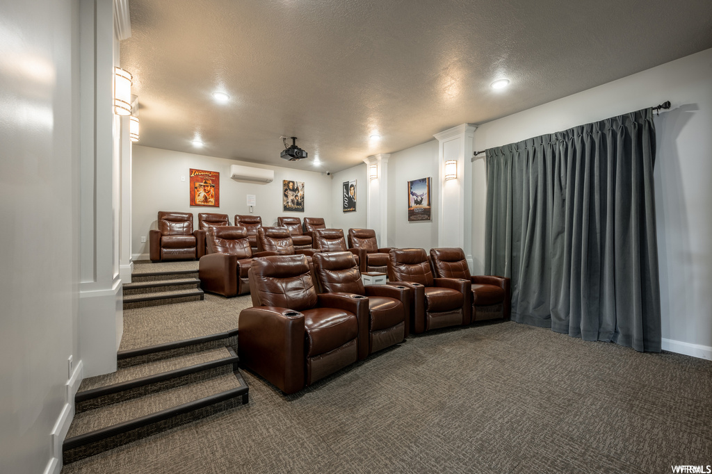 Cinema room featuring a wall mounted air conditioner, a textured ceiling, and dark carpet