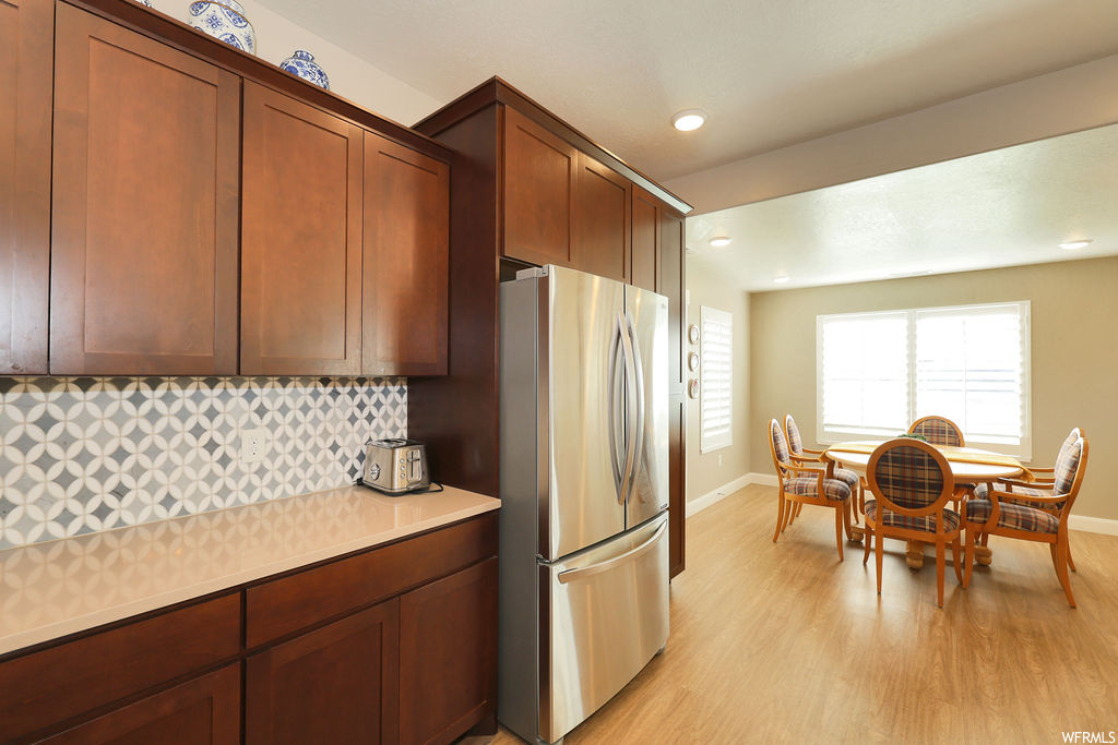 Kitchen featuring light hardwood floors, stainless steel fridge, and backsplash