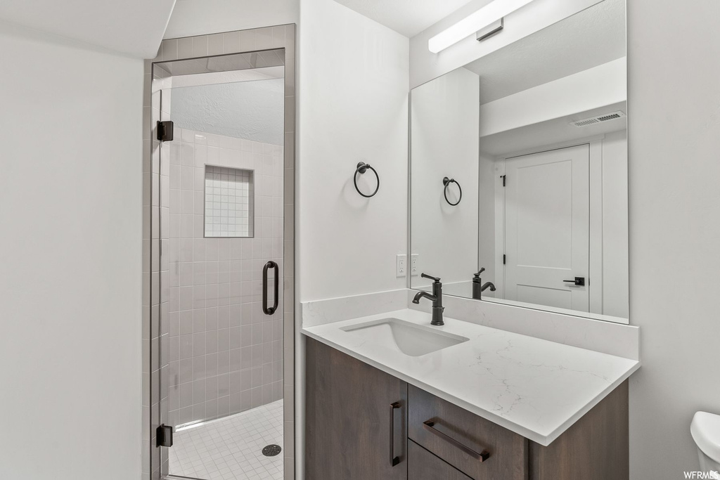 Bathroom with toilet, large vanity, and walk in shower