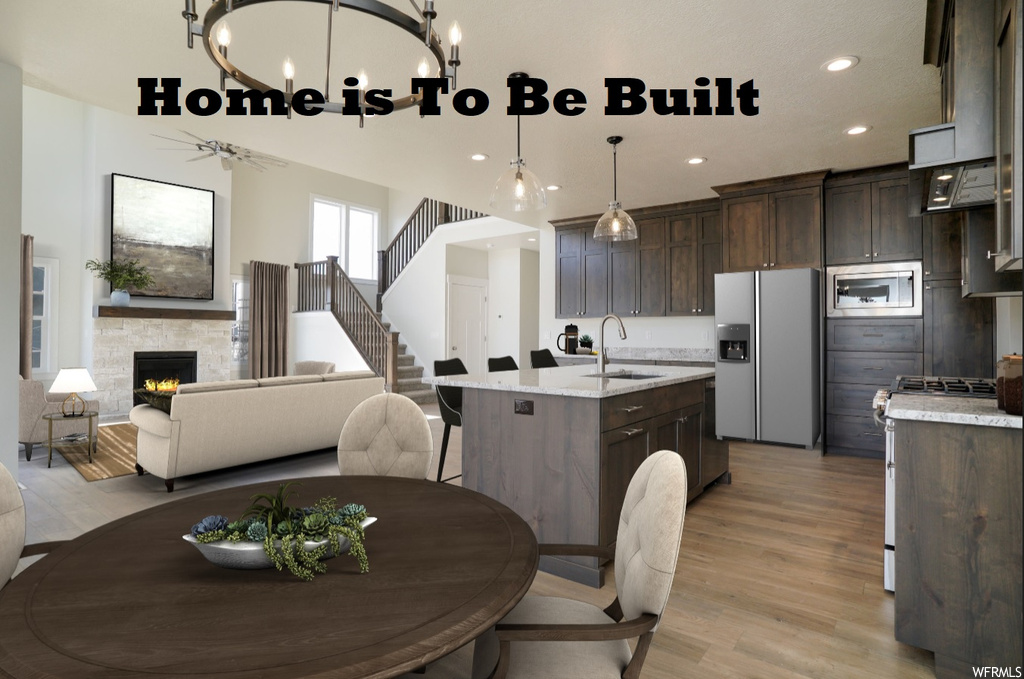 Kitchen featuring a kitchen island, stainless steel appliances, pendant lighting, a chandelier, dark brown cabinetry, fume extractor, light countertops, kitchen island with sink, and light hardwood floors