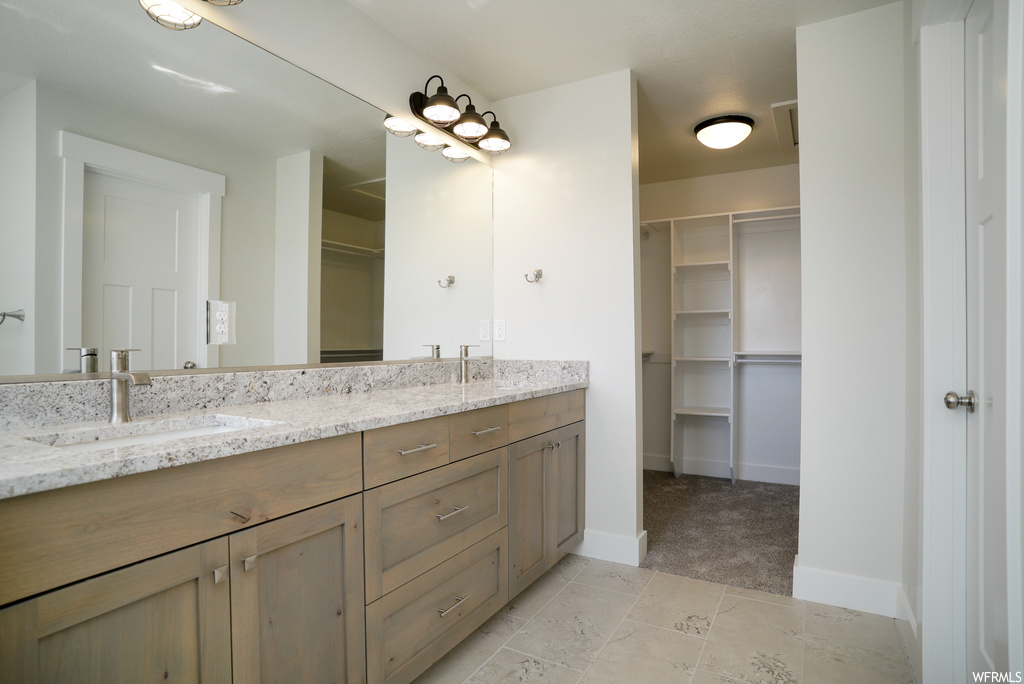 Bathroom featuring double sink vanity, mirror, and light tile floors