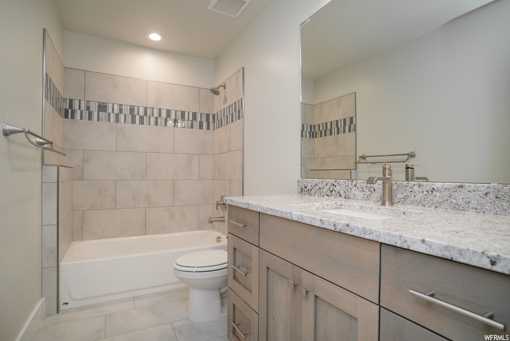 Full bathroom featuring tiled shower / bath combo, oversized vanity, light tile flooring, and mirror