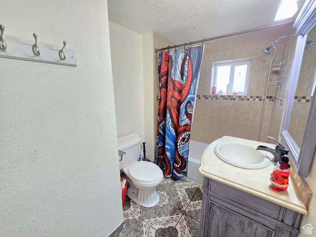 Full bathroom with tile flooring, shower / tub combo, vanity, and toilet