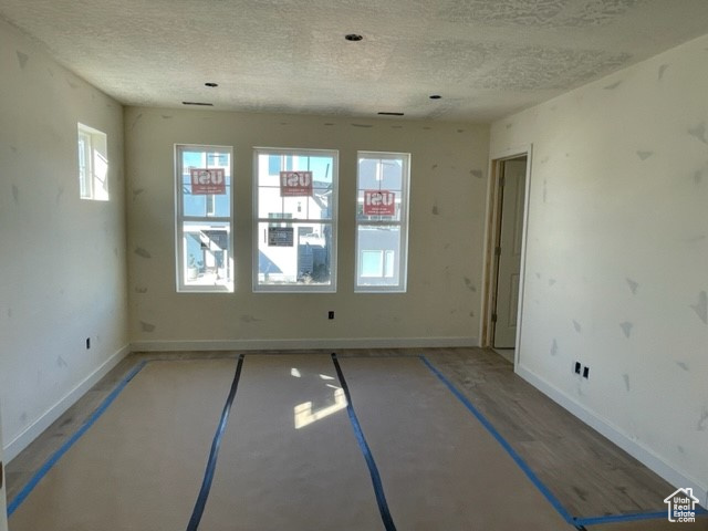 Unfurnished room featuring a textured ceiling and hardwood / wood-style flooring