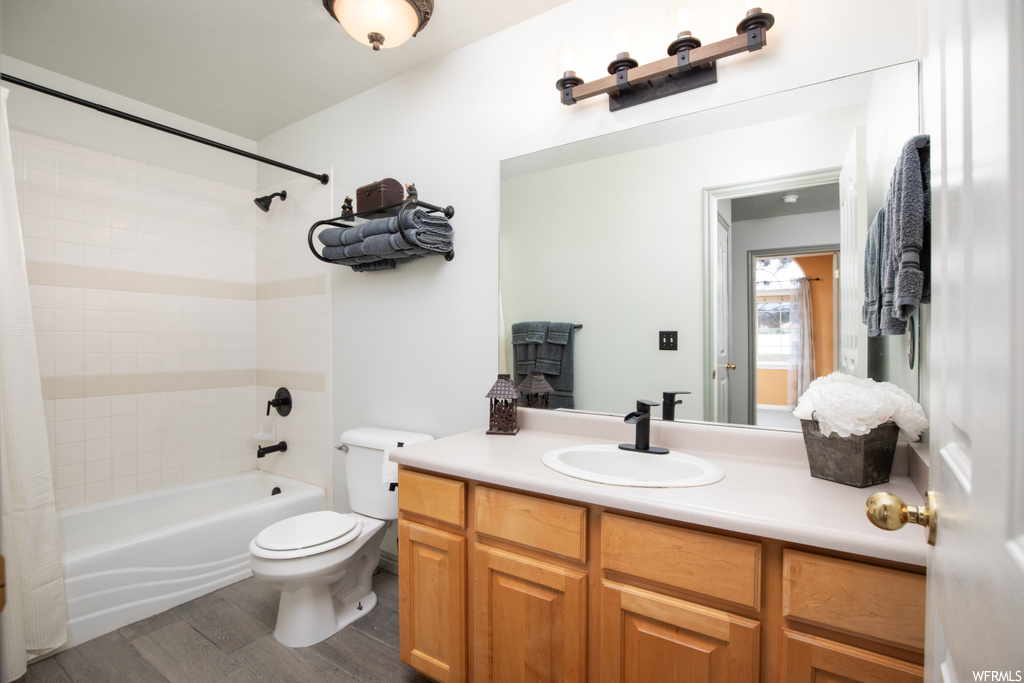 Full bathroom with light hardwood floors, shower / bath combo, mirror, and vanity