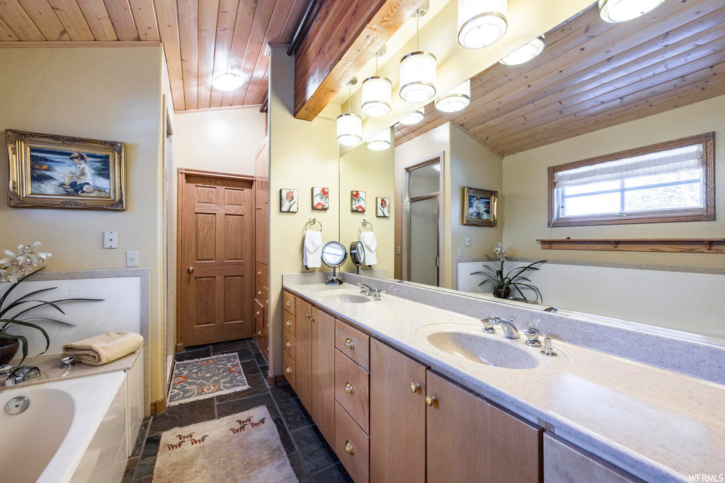 Bathroom featuring a bathing tub, dual large bowl vanity, tile floors, mirror, wood ceiling, and vaulted ceiling