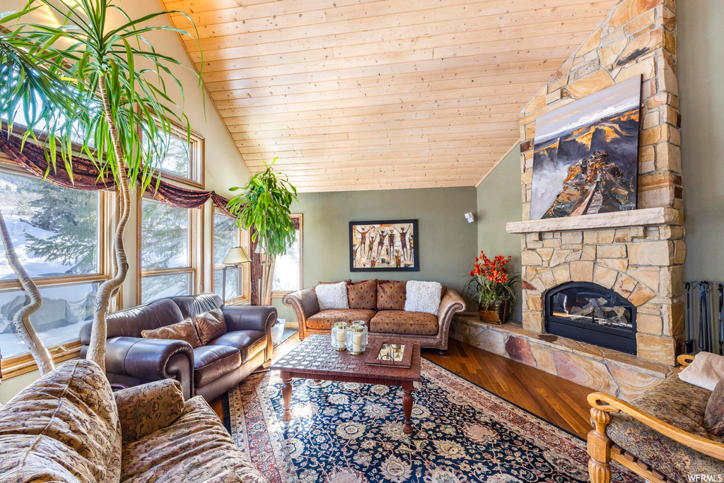 Living room featuring vaulted ceiling, hardwood floors, a fireplace, wood ceiling, and a high ceiling