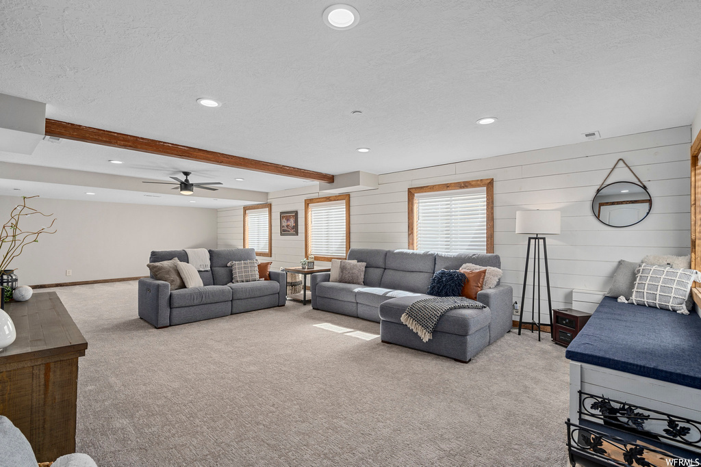 Living room featuring ceiling fan, light carpet, beam ceiling, and a textured ceiling