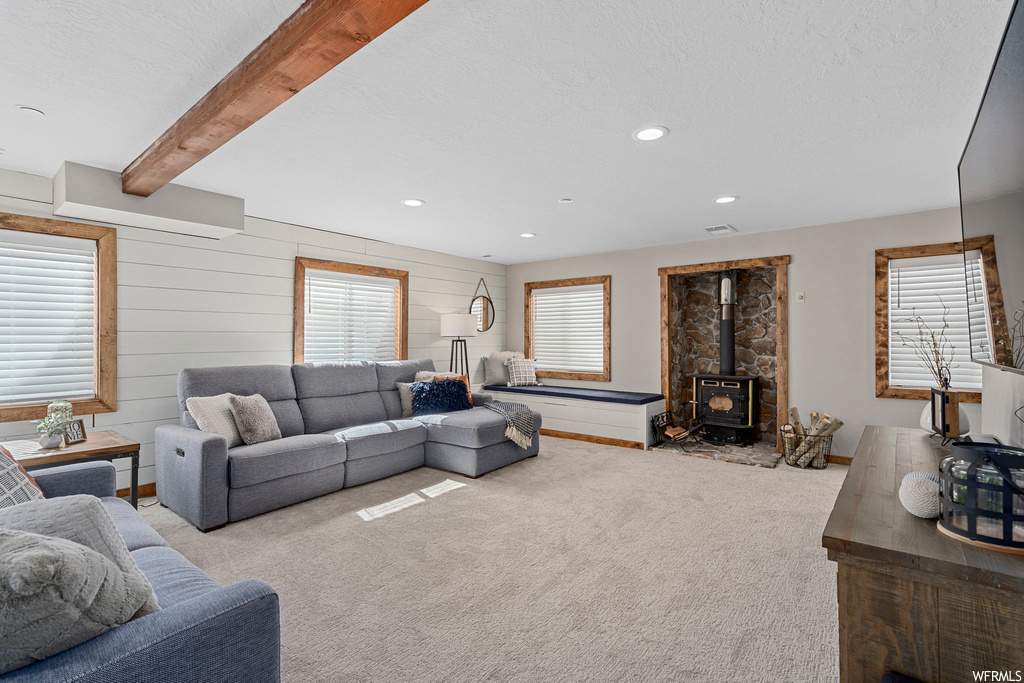 Living room featuring beam ceiling, a fireplace, and light carpet