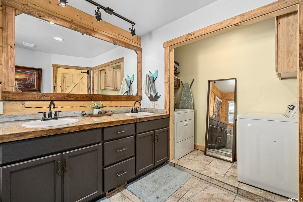 Bathroom with double sink vanity, a shower, mirror, track lighting, and light tile floors