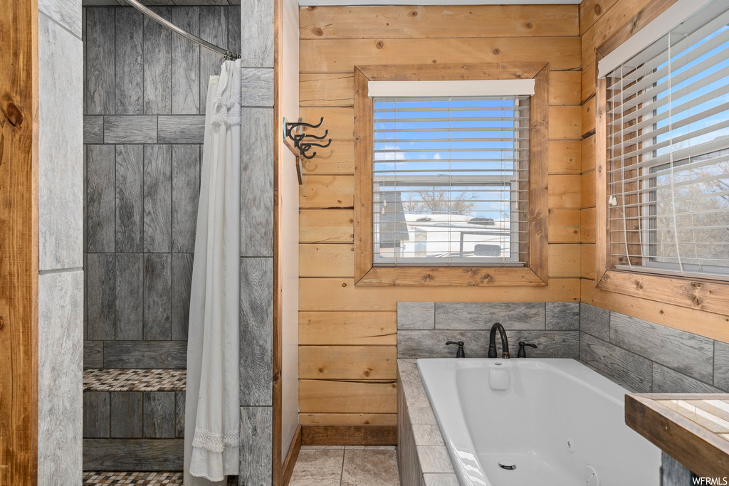 Bathroom with shower with separate bathtub, wooden walls, and light tile floors