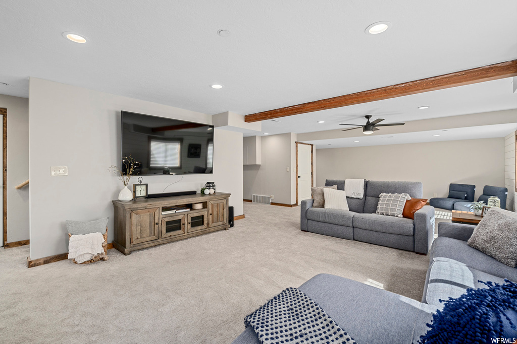 Carpeted living room with beamed ceiling and ceiling fan