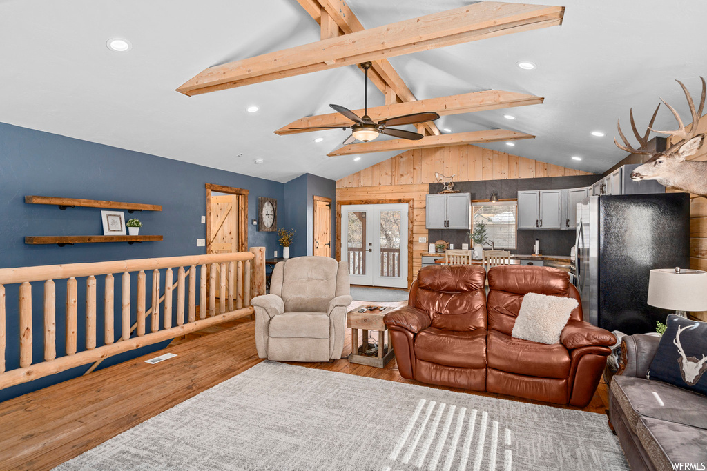 Living room with vaulted ceiling with beams, light hardwood floors, and ceiling fan