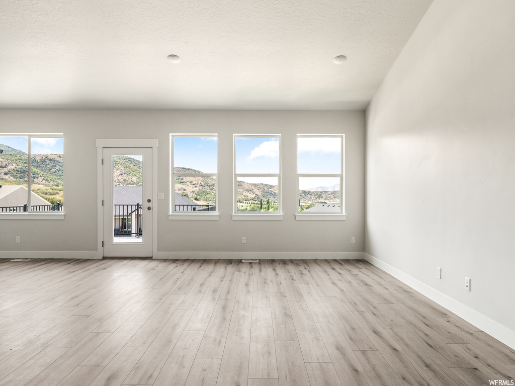 Wood floored spare room featuring plenty of natural light