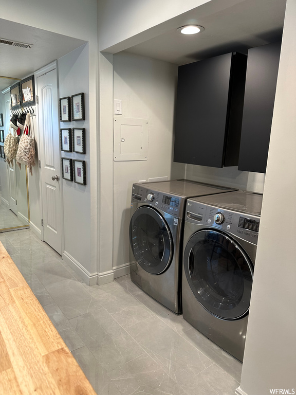 Clothes washing area featuring light tile flooring and washing machine and clothes dryer