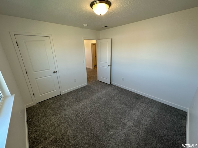 Bedroom with a textured ceiling and dark carpet