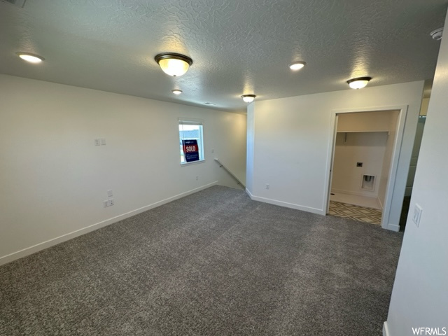 Empty room with carpet and a textured ceiling