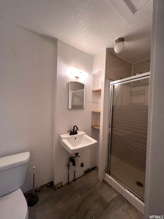 Bathroom with sink, a textured ceiling, a shower with shower door, and mirror