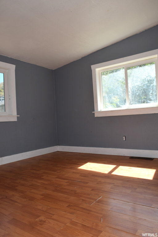 Unfurnished room featuring a skylight and dark hardwood flooring