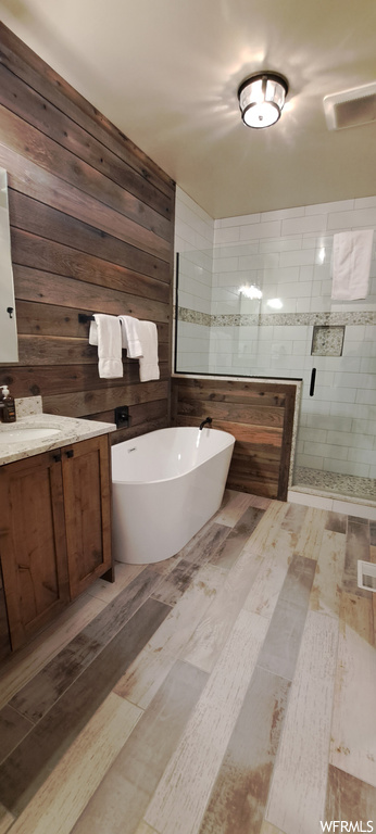 Bathroom with wood walls, vanity, and separate shower and tub enclosures