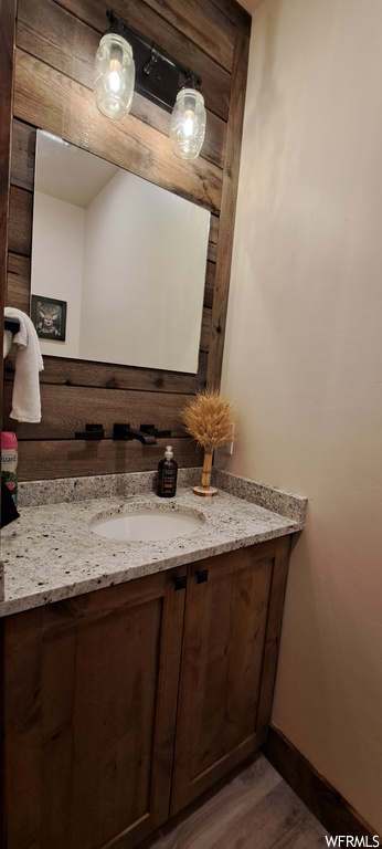 Bathroom with hardwood floors, vanity, and mirror