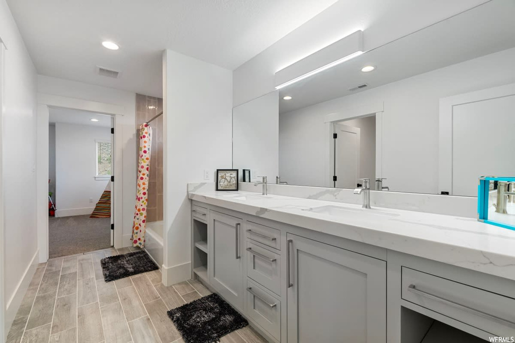 Bathroom featuring shower / bath combination with curtain, mirror, light hardwood floors, and dual vanity