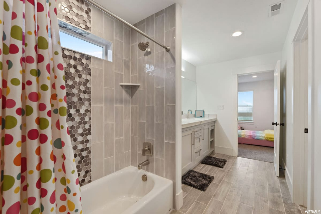 Bathroom with vanity, plenty of natural light, mirror, light hardwood flooring, and shower / bath combo