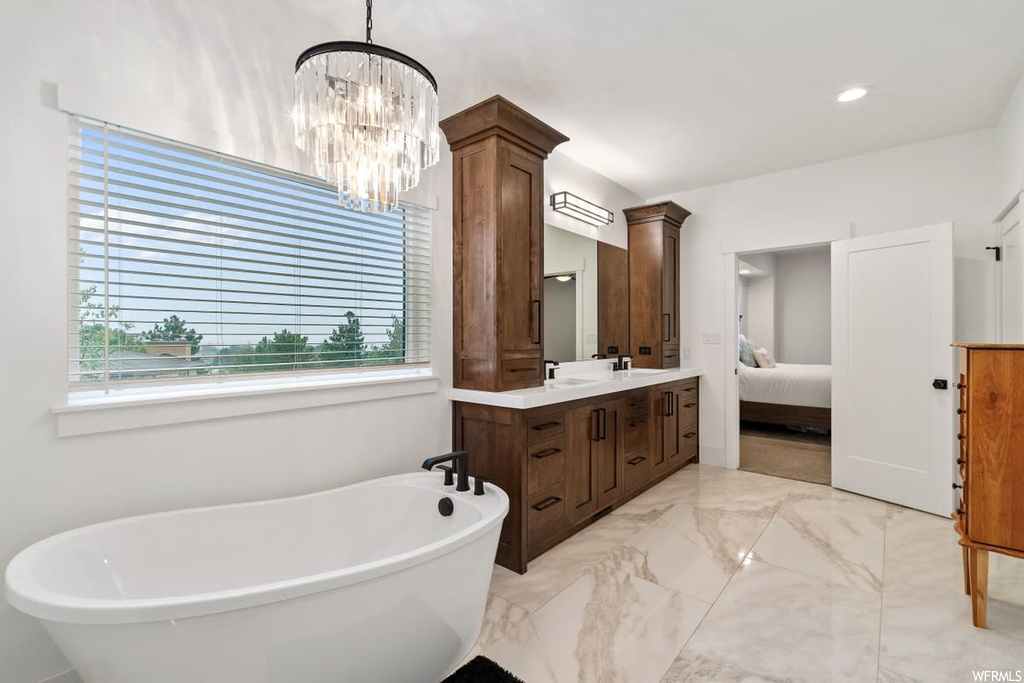 Bathroom with vanity with extensive cabinet space, mirror, a healthy amount of sunlight, light tile floors, and a bath