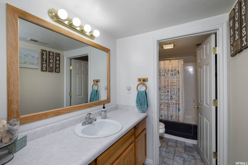 Bathroom with vanity with extensive cabinet space, mirror, and light tile floors