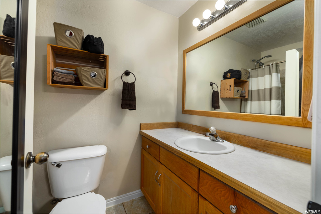 Bathroom featuring vanity, mirror, a textured ceiling, and light tile floors