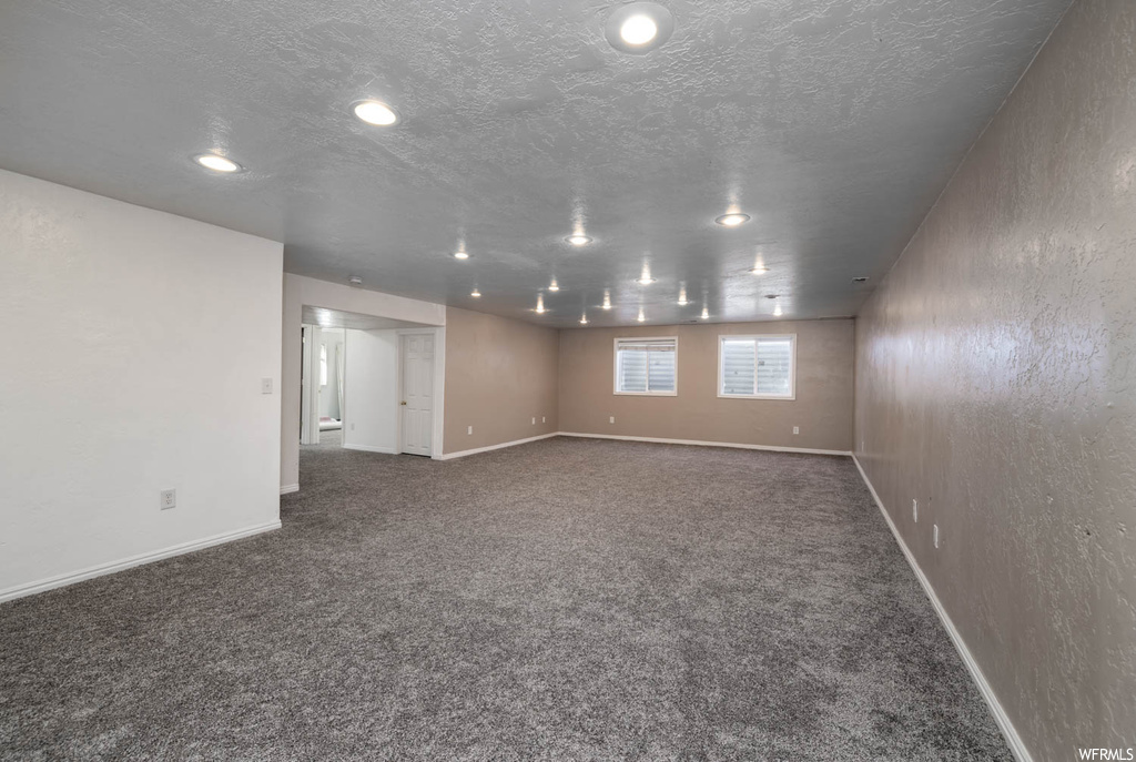 Spare room featuring a textured ceiling and dark carpet