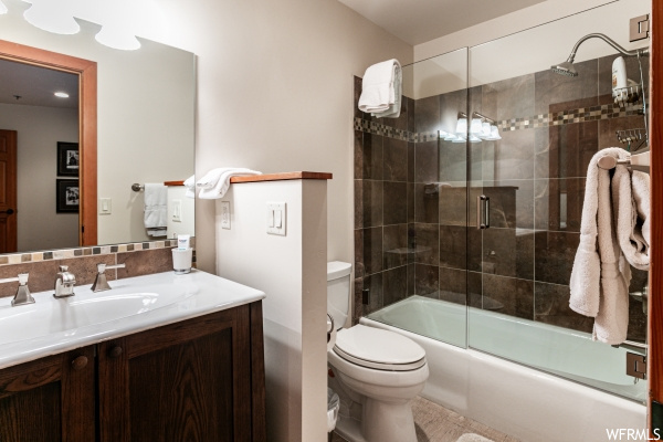Full bathroom featuring combined bath / shower with glass door, toilet, and vanity