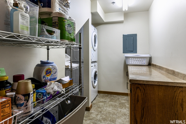 Clothes washing area featuring stacked washer and dryer and light tile floors