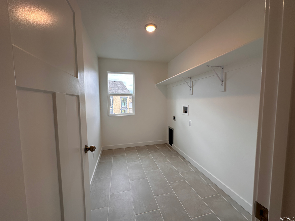 Clothes washing area with light tile flooring, hookup for an electric dryer, and washer hookup
