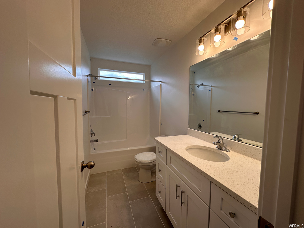 Full bathroom featuring shower / bathing tub combination, toilet, a textured ceiling, tile floors, and vanity with extensive cabinet space