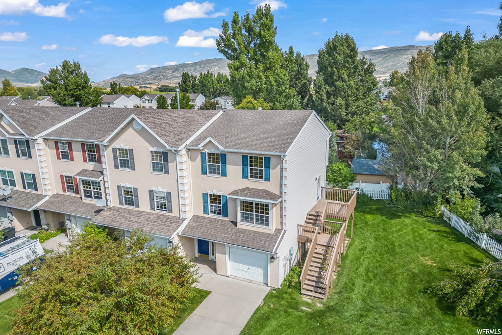 Multi unit property with garage, a front yard, and a mountain view