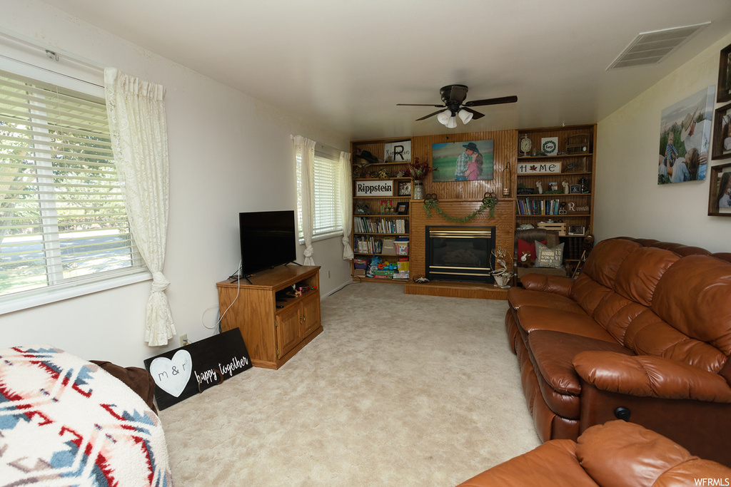 Living room featuring light carpet, a fireplace, and ceiling fan