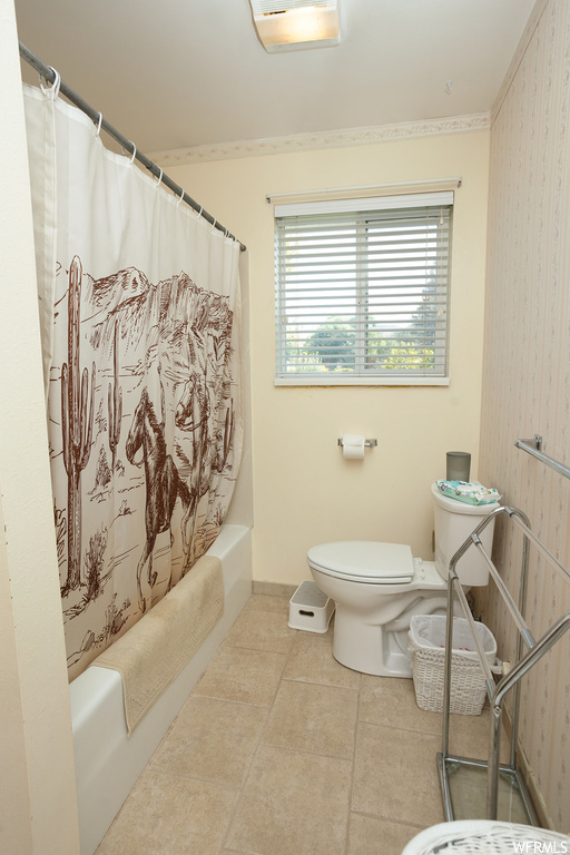 Bathroom featuring light tile flooring and shower / bath combination with curtain