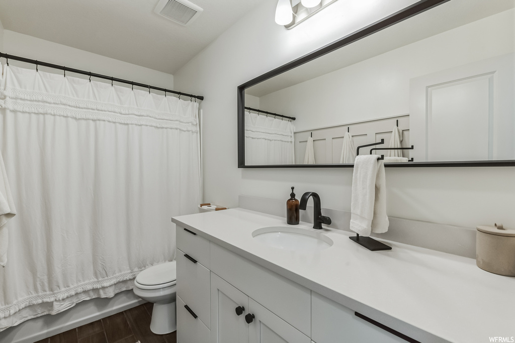 Bathroom with oversized vanity, mirror, and hardwood flooring