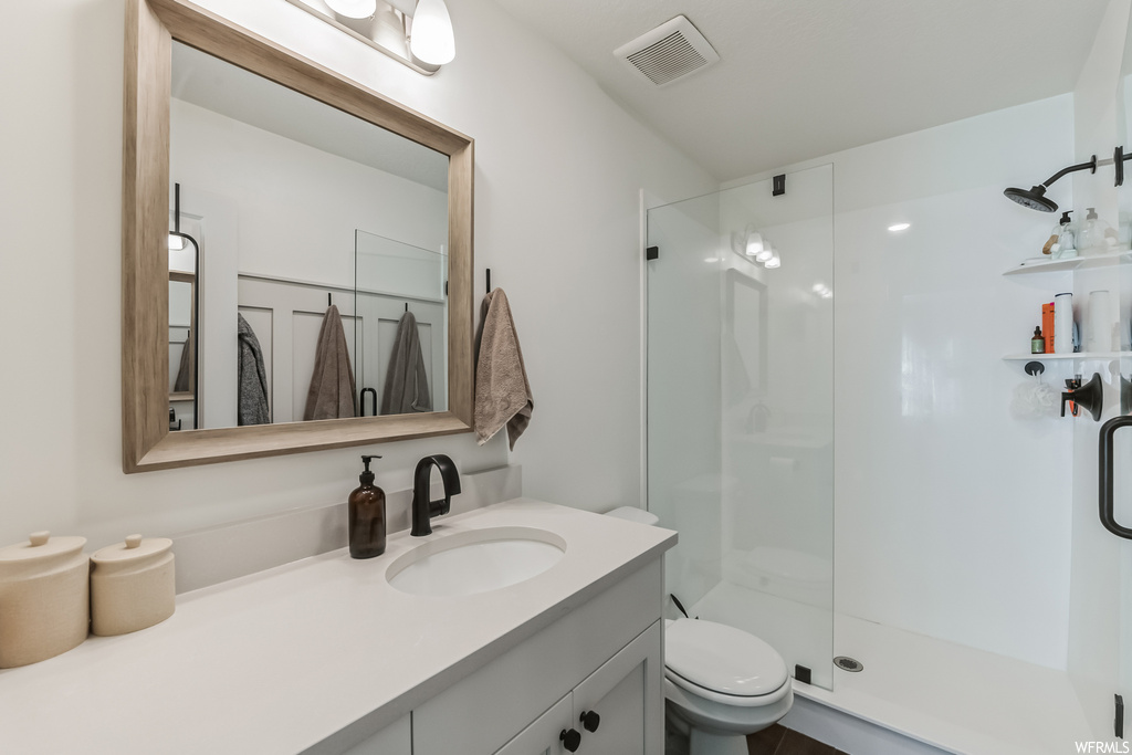 Bathroom featuring oversized vanity, mirror, and a shower with door