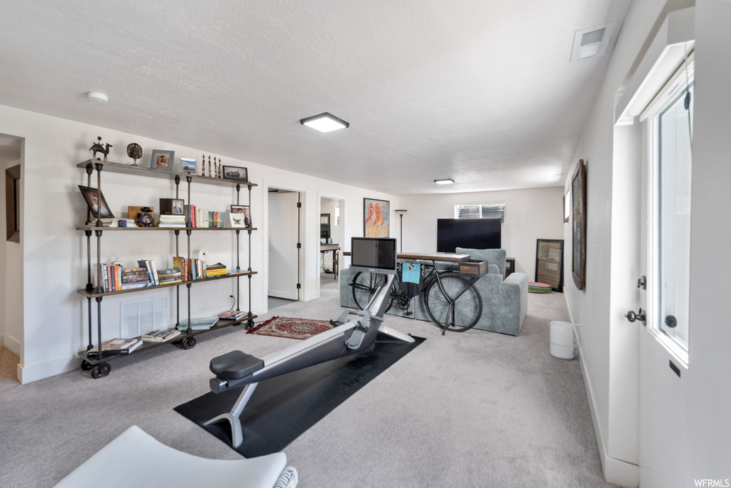 Exercise room featuring light carpet and a textured ceiling