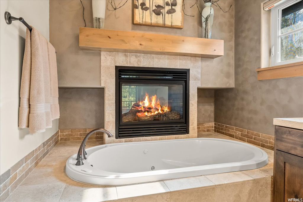 Bathroom featuring a fireplace and a relaxing tiled bath