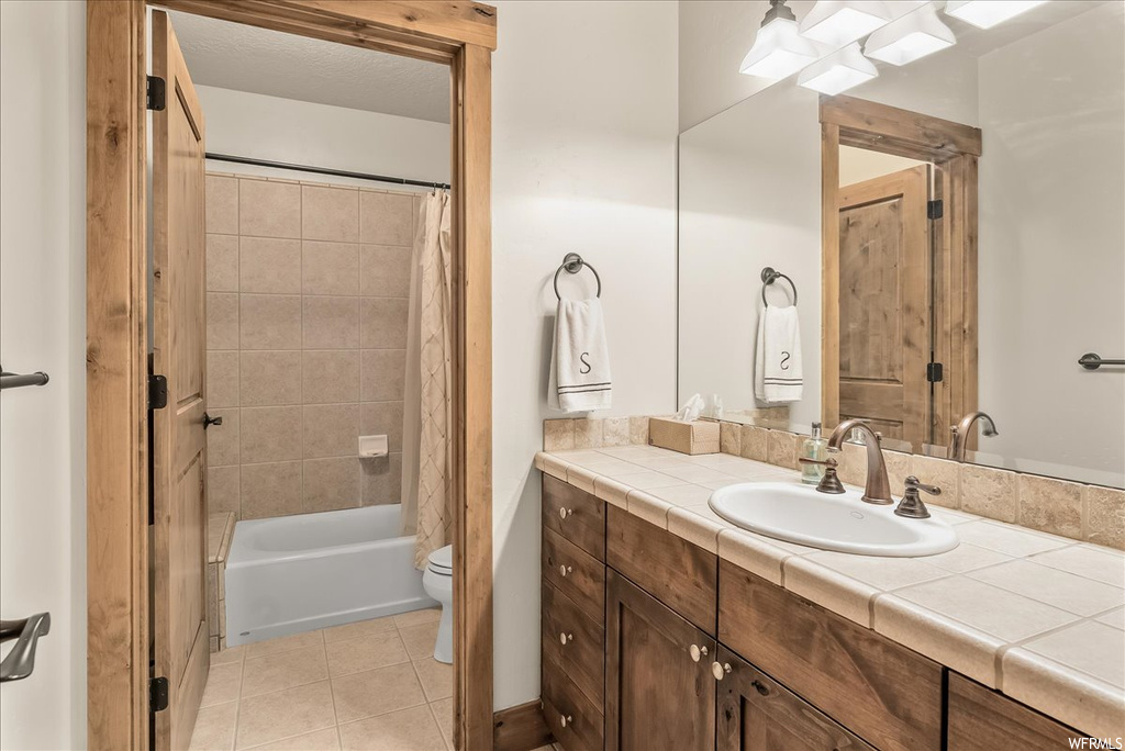 Full bathroom featuring light tile floors, shower / bath combo, mirror, and vanity