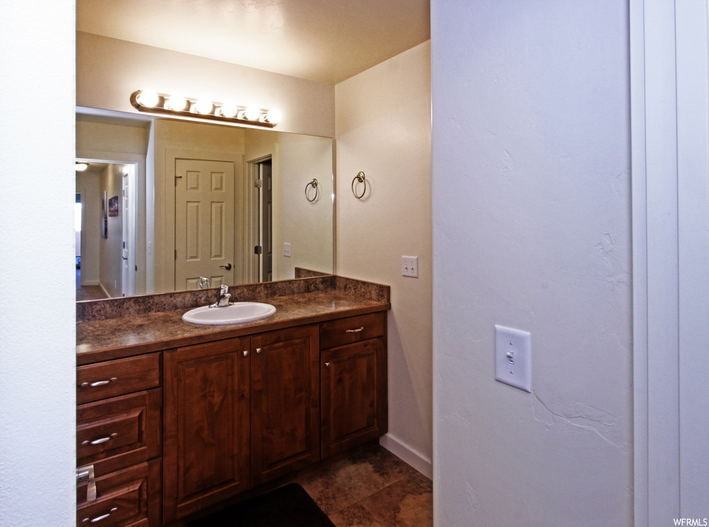 Bathroom featuring dark tile flooring, oversized vanity, and mirror
